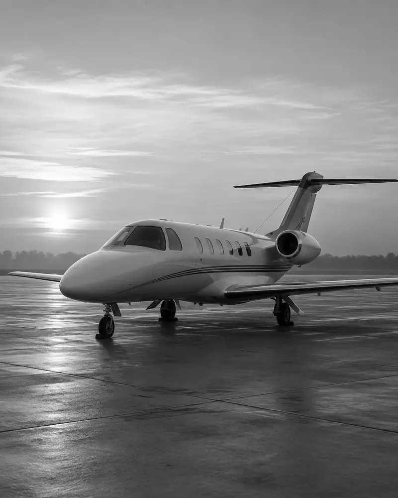 Light business jet parked on an apron at dawn